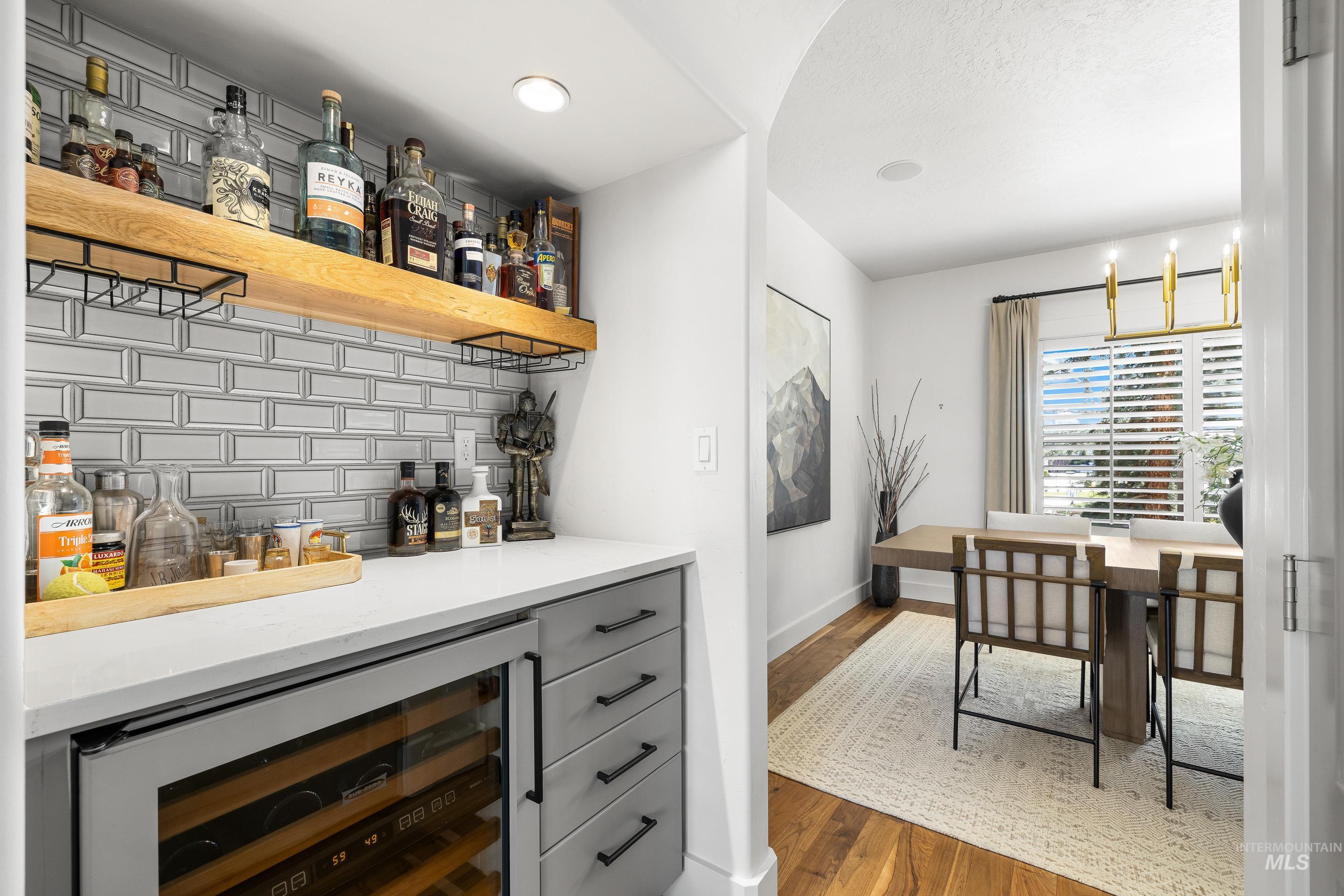 1166 East Rivers End Drive Eagle, ID 83616 - Photo 21 of 50 Indoor dry bar featuring wine cooler, decorative backsplash, open shelves, gray cabinetry, and dark wood finished floors