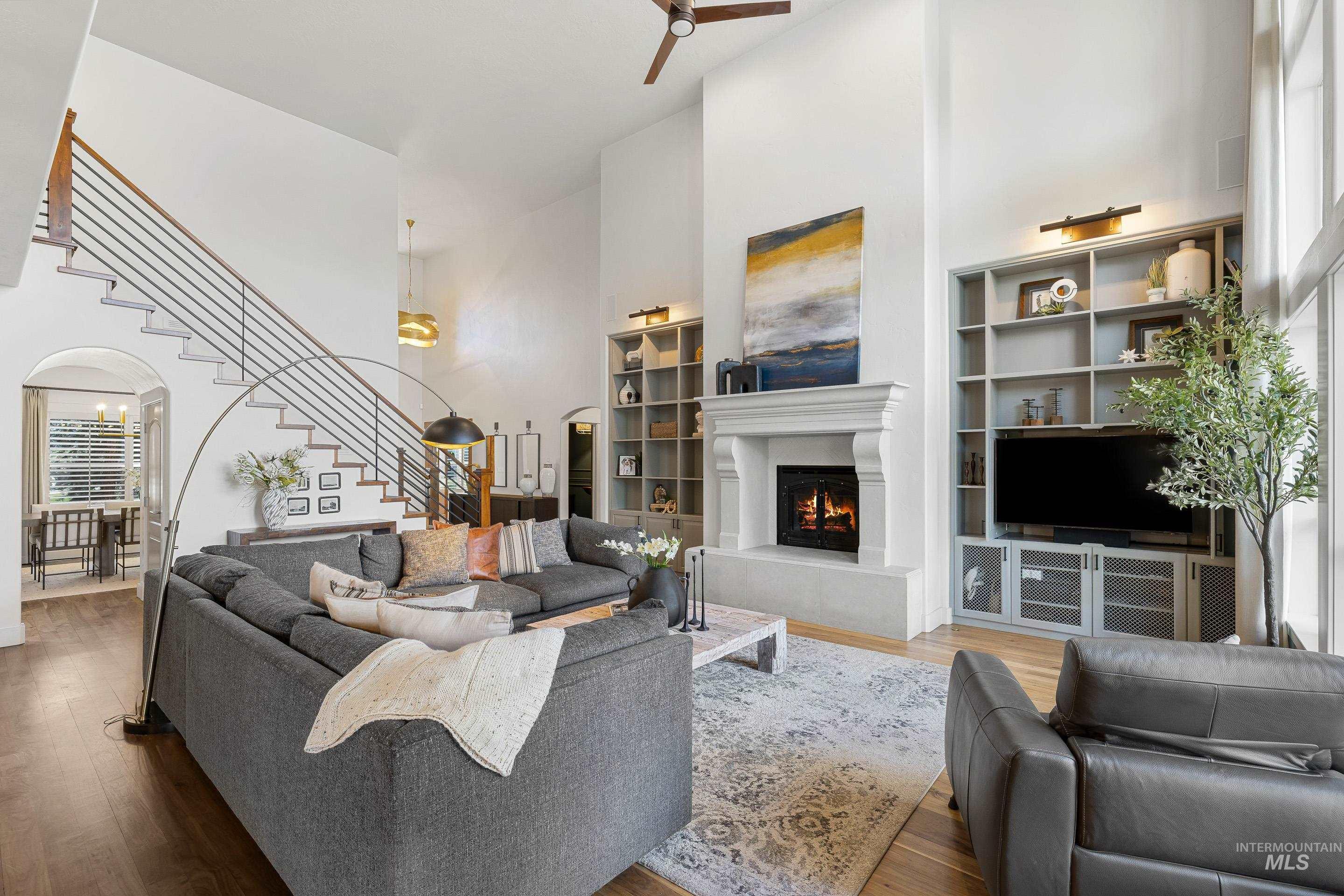 1166 East Rivers End Drive Eagle, ID 83616 - Photo 4 of 50 Living room with a high ceiling, wood finished floors, a warm lit fireplace, and arched walkways