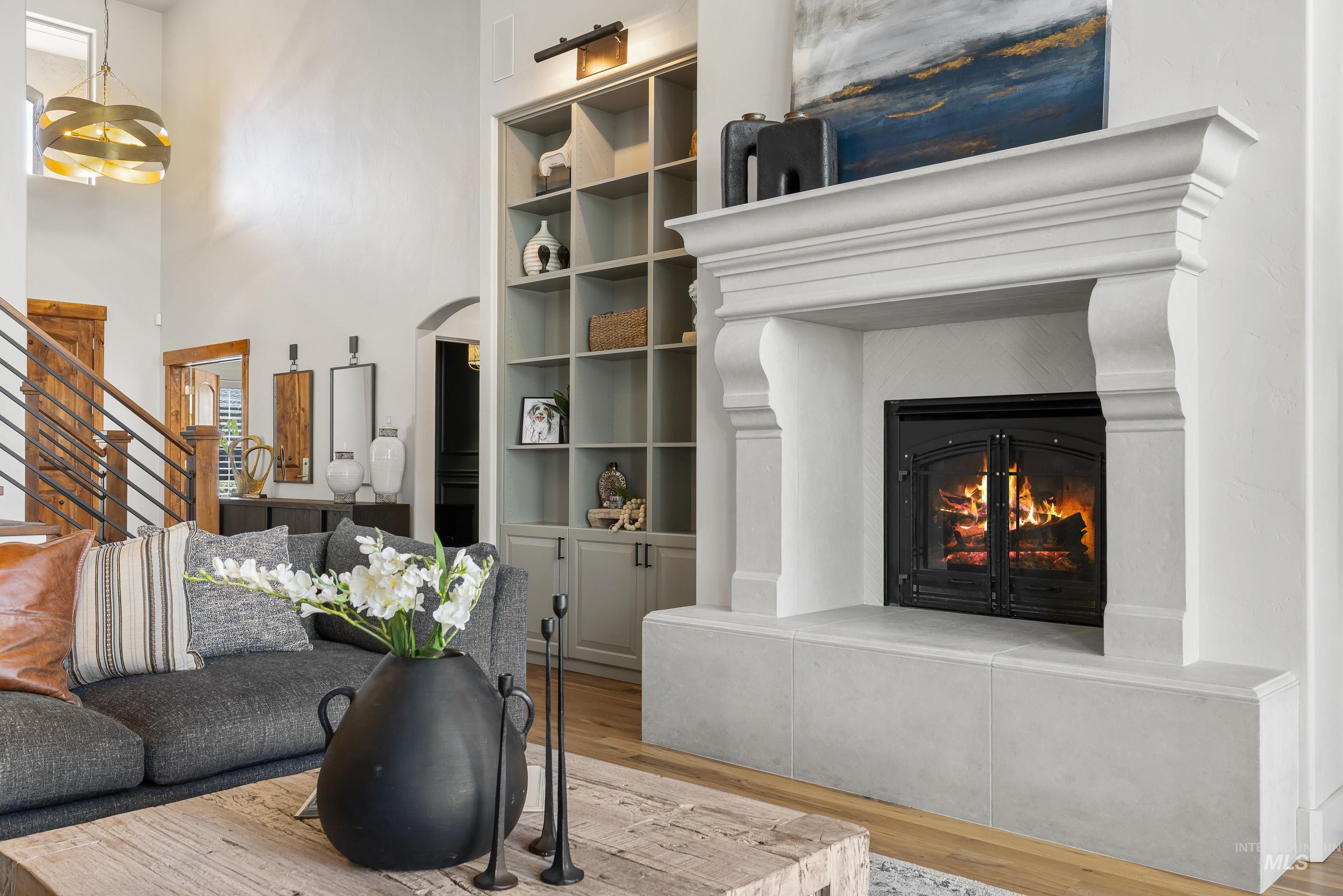 1166 East Rivers End Drive Eagle, ID 83616 - Photo 6 of 50 Living area featuring arched walkways, wood finished floors, a glass covered fireplace, suspended lighting, and built in shelves