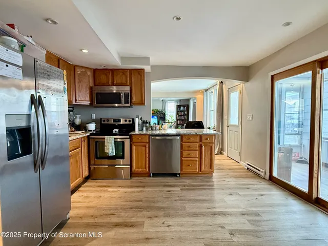 a large kitchen with stainless steel appliances granite countertop a stove a sink dishwasher a refrigerator and a oven with wooden floor