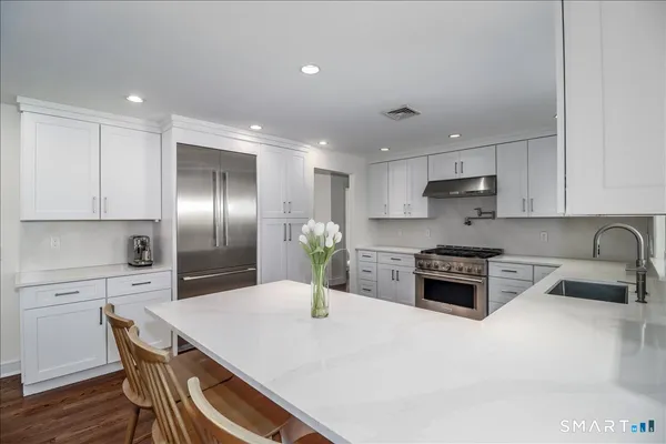 a kitchen with a refrigerator a stove a sink a dining table and chairs