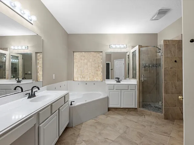 a bathroom with a tub sink shower and mirror