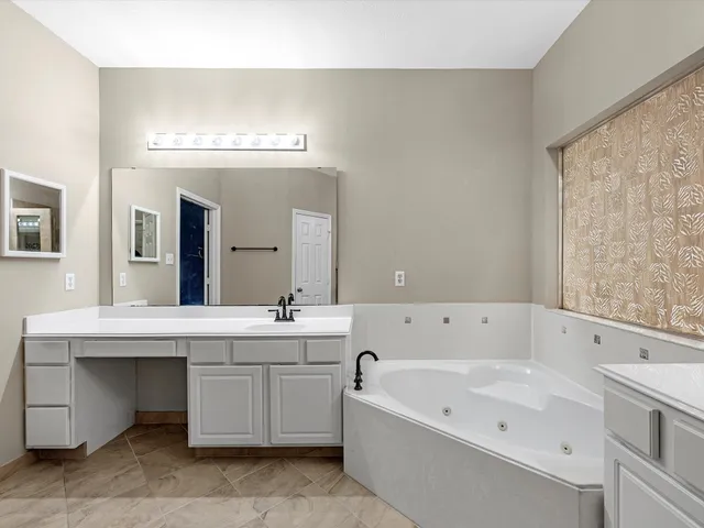 a bathroom with a tub a sink and mirror