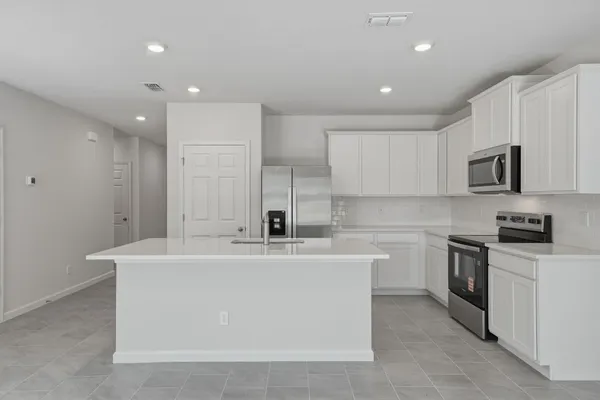 a view of a kitchen with kitchen island a sink stainless steel appliances and cabinets