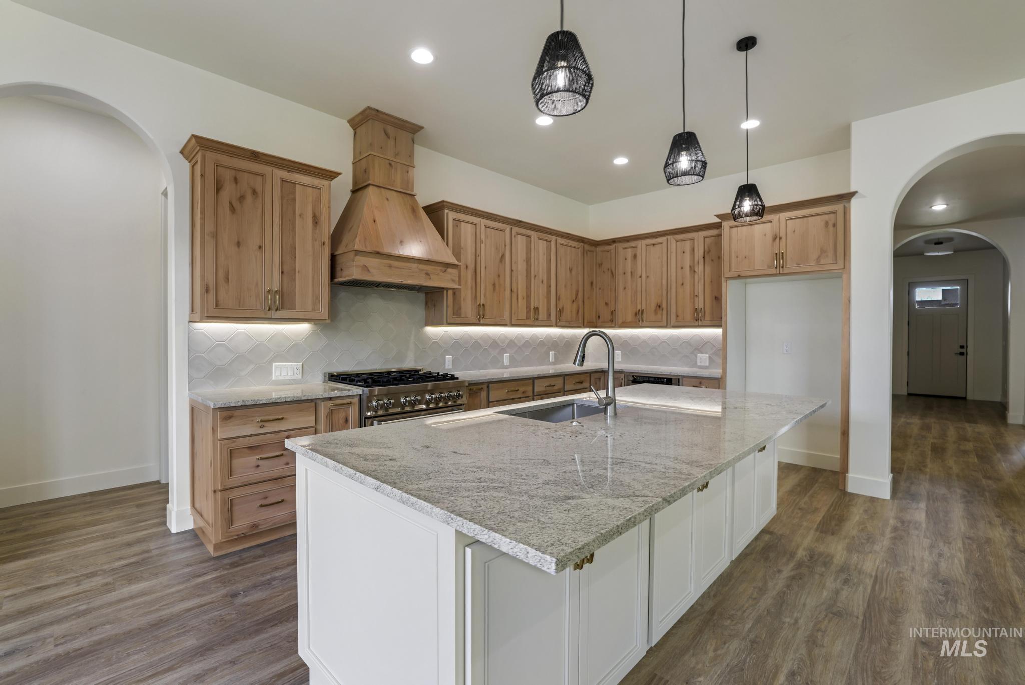 542 Falling Leaf Lane Twin Falls, ID 83301 - Photo 15 of 38 Kitchen featuring arched walkways, tasteful backsplash, light stone countertops, pendant lighting, and recessed lighting