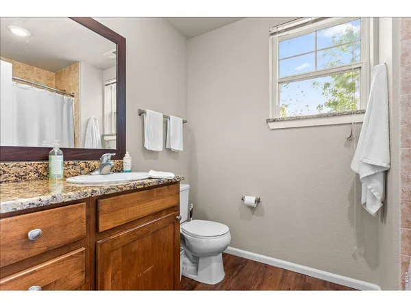 a bathroom with a granite countertop toilet a sink a mirror and a window