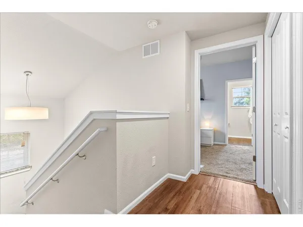 a view of an empty room with wooden floor and a bathroom