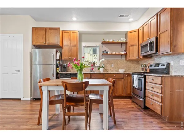 a kitchen with stainless steel appliances granite countertop a table chairs and a refrigerator