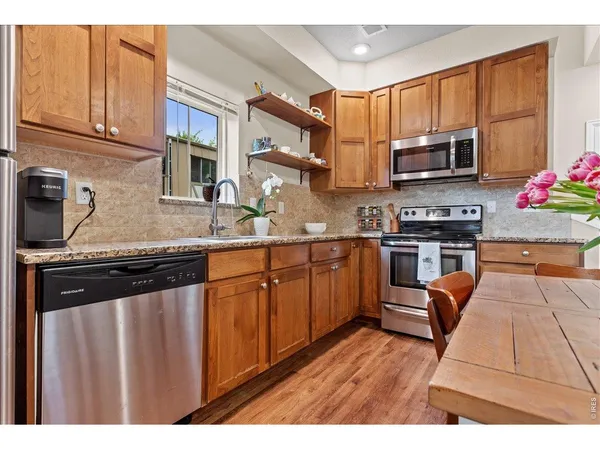 a kitchen with stainless steel appliances granite countertop a sink dishwasher stove and microwave with wooden cabinets