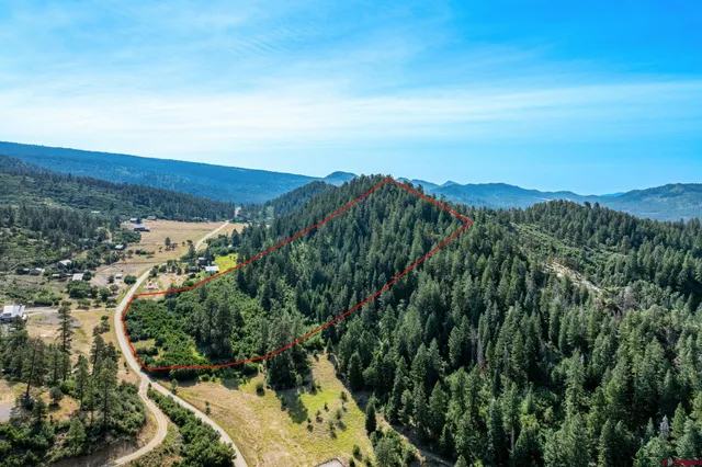 a view of a lush green field with mountains in the background