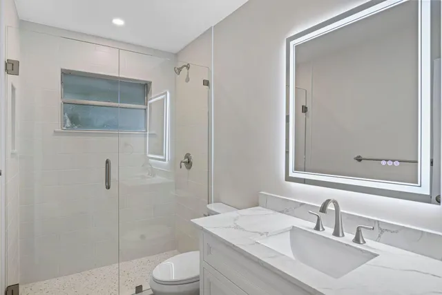 a bathroom with a sink a toilet and shower