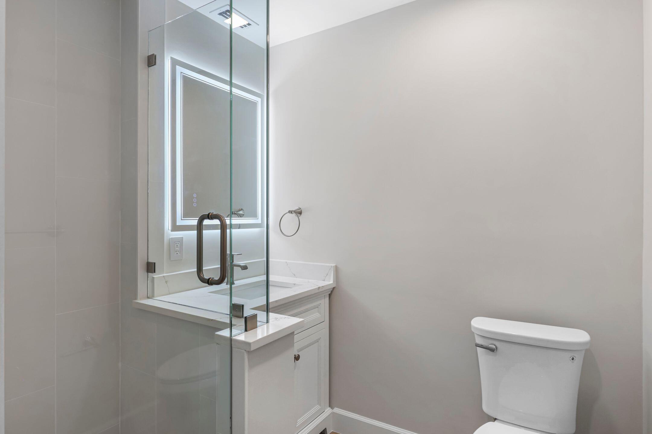 2929 Southeast Ocean Boulevard, Unit 1406 Stuart, FL 34996 - Photo 19 of 27 a bathroom with a sink a toilet and mirror