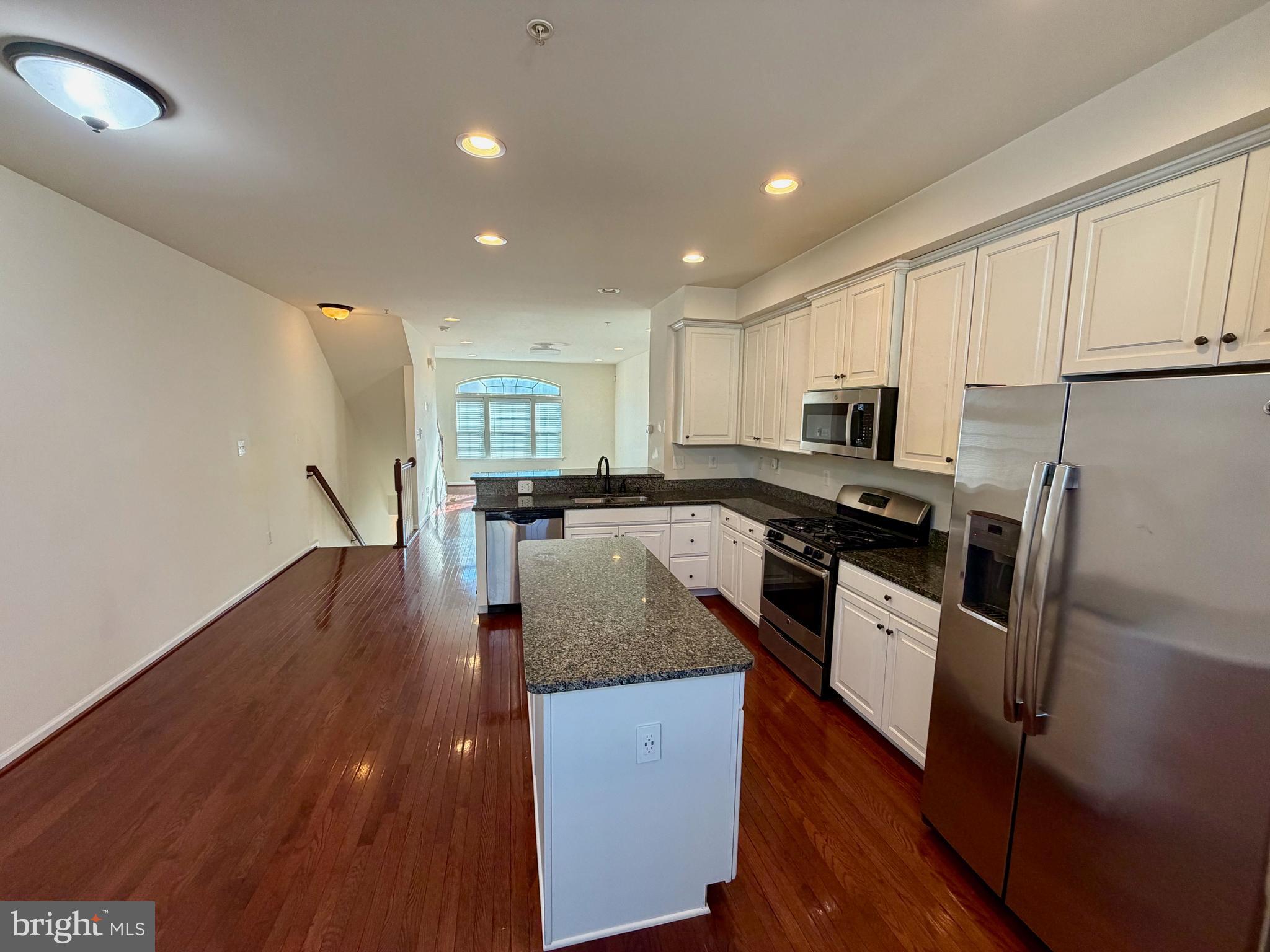 7729 Duncannon Lane Hanover, MD 21076 - Photo 8 of 26 a kitchen with granite countertop a refrigerator a stove top oven and white cabinets