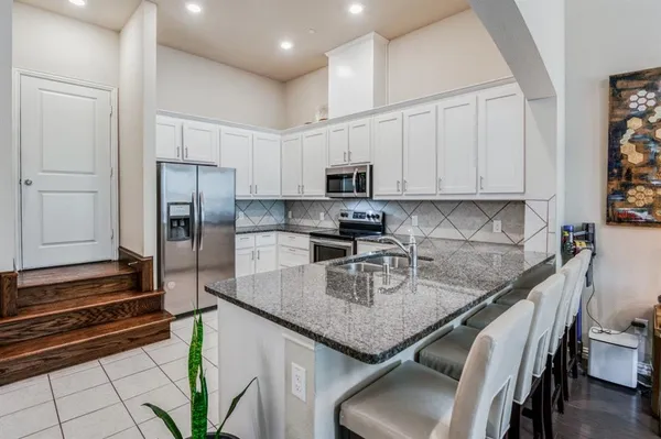 a kitchen with stainless steel appliances granite countertop a sink refrigerator and microwave