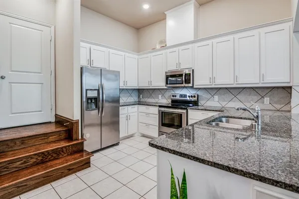a kitchen with granite countertop a refrigerator sink and cabinets