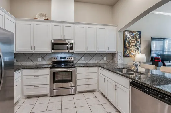 a kitchen with granite countertop white cabinets and appliances
