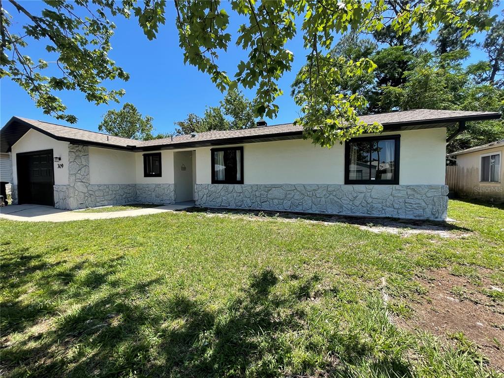 a front view of house with yard and trees in the background