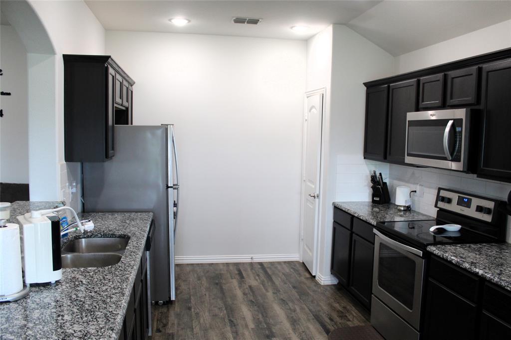 515 Cottage Row Mabank, TX 75147 - Photo 5 of 16 a kitchen with stainless steel appliances granite countertop a sink stove and refrigerator