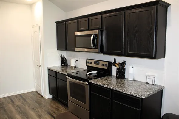 a kitchen with granite countertop a stove and a microwave with wooden floor