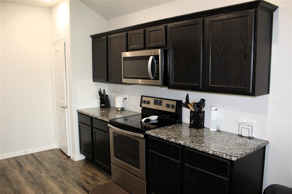 515 Cottage Row Mabank, TX 75147 - Photo 6 of 16 a kitchen with granite countertop a stove and a microwave with wooden floor