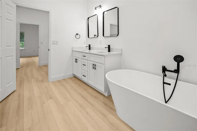 a bathroom with a bathtub a sink a mirror and shower