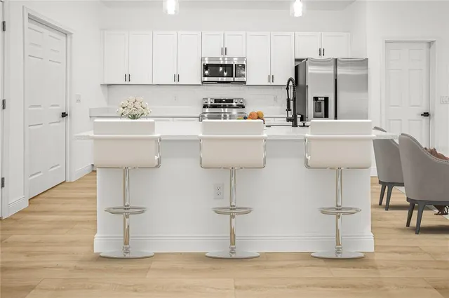a kitchen with stainless steel appliances a sink cabinets and wooden floor