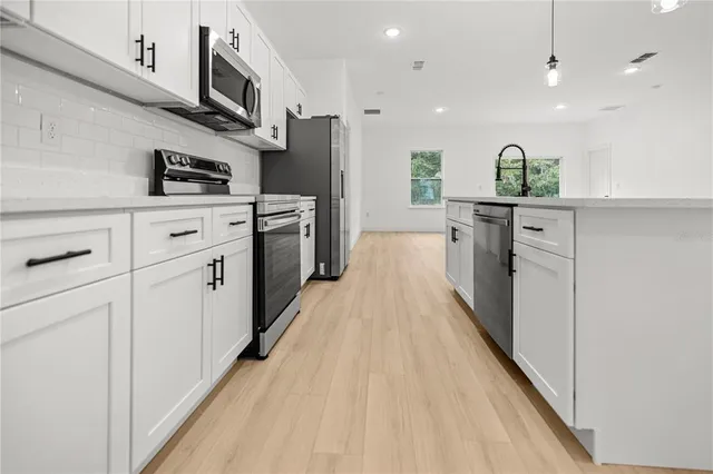 a kitchen with white cabinets and stainless steel appliances