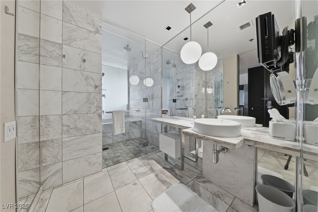 4381 West Flamingo Road, Unit 11308 Las Vegas, NV 89103 - Photo 11 of 26 Full bathroom with a shower stall, vanity, tile walls, and light marble finish floors