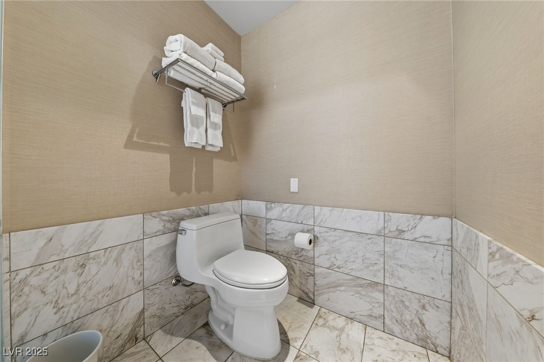 4381 West Flamingo Road, Unit 11308 Las Vegas, NV 89103 - Photo 12 of 26 Bathroom featuring tile walls, wainscoting, and wallpapered walls