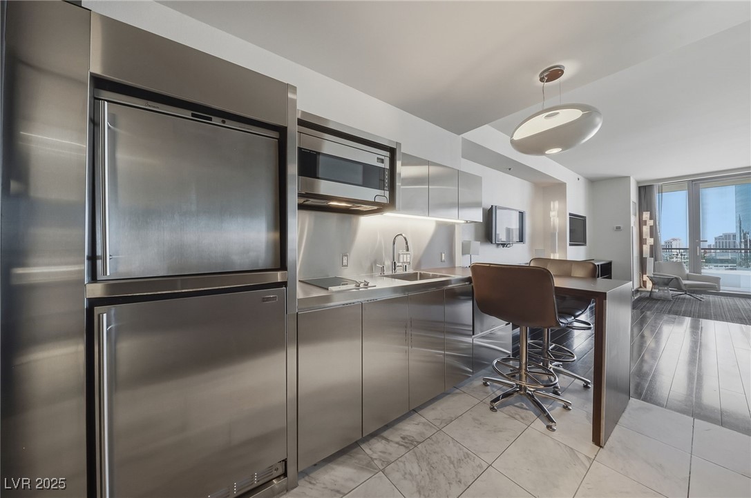 4381 West Flamingo Road, Unit 11308 Las Vegas, NV 89103 - Photo 26 of 26 Kitchen with hanging light fixtures, stainless steel microwave, modern cabinets, open floor plan, and a desk