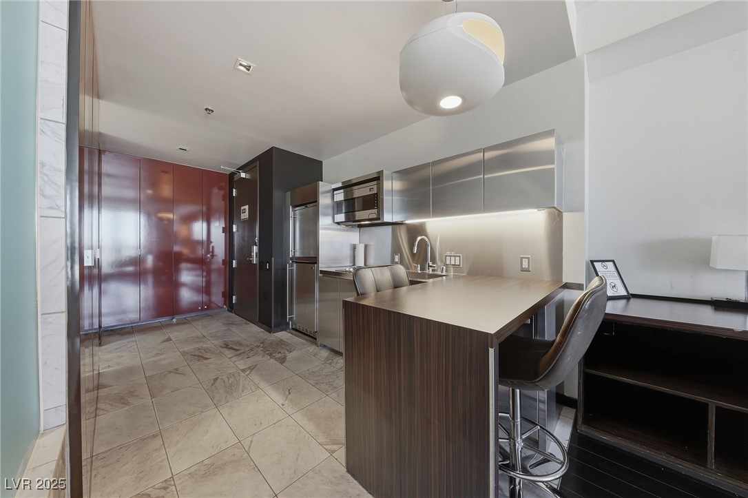 4381 West Flamingo Road, Unit 11308 Las Vegas, NV 89103 - Photo 3 of 26 Kitchen featuring a breakfast bar, a peninsula, appliances with stainless steel finishes, and modern cabinets