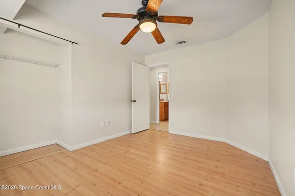 an empty room with wooden floor fan and windows