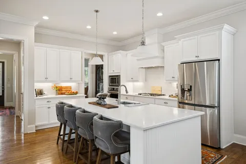 a large white kitchen with stainless steel appliances granite countertop a stove and a sink