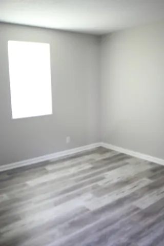 an empty room with wooden floor and a window