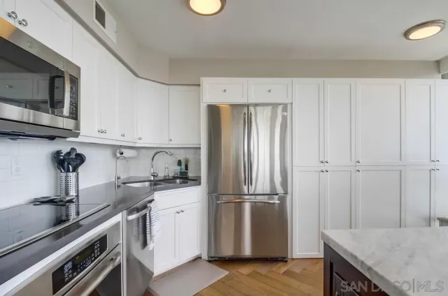 a kitchen with a sink stainless steel appliances and white cabinets