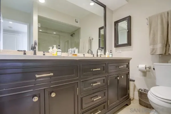 a bathroom with a granite countertop toilet sink and mirror