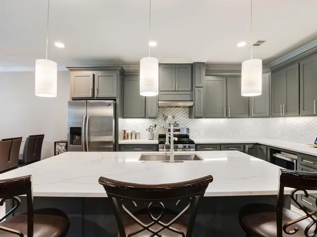 a kitchen with stainless steel appliances kitchen island a table chairs in it and wooden floors