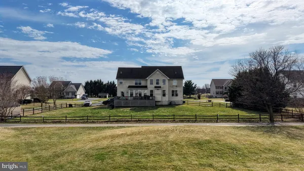 a view of swimming pool that has lawn chairs plants and large tree