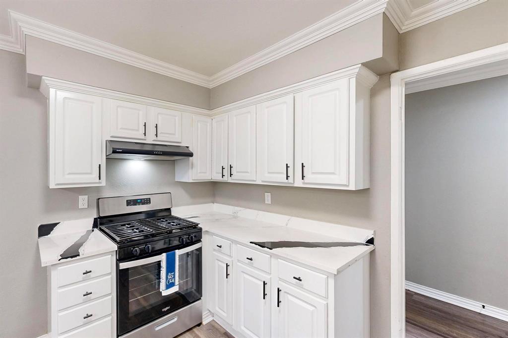 3264 Northaven Road Dallas, TX 75229 - Photo 10 of 35 Kitchen with stainless steel gas range, under cabinet range hood, white cabinetry, and ornamental molding