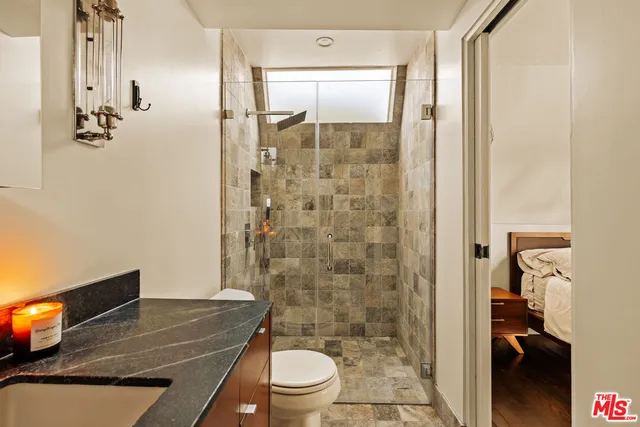 a bathroom with a granite countertop bathtub shower sink mirror and toilet