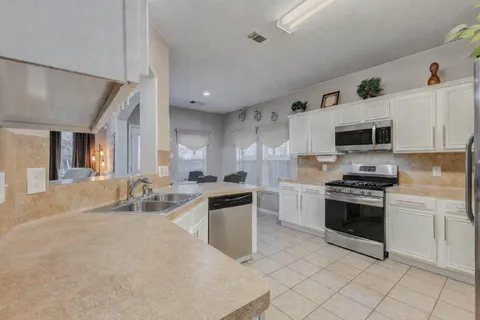 a kitchen with stainless steel appliances granite countertop a stove top oven a sink dishwasher and a refrigerator with wooden floor