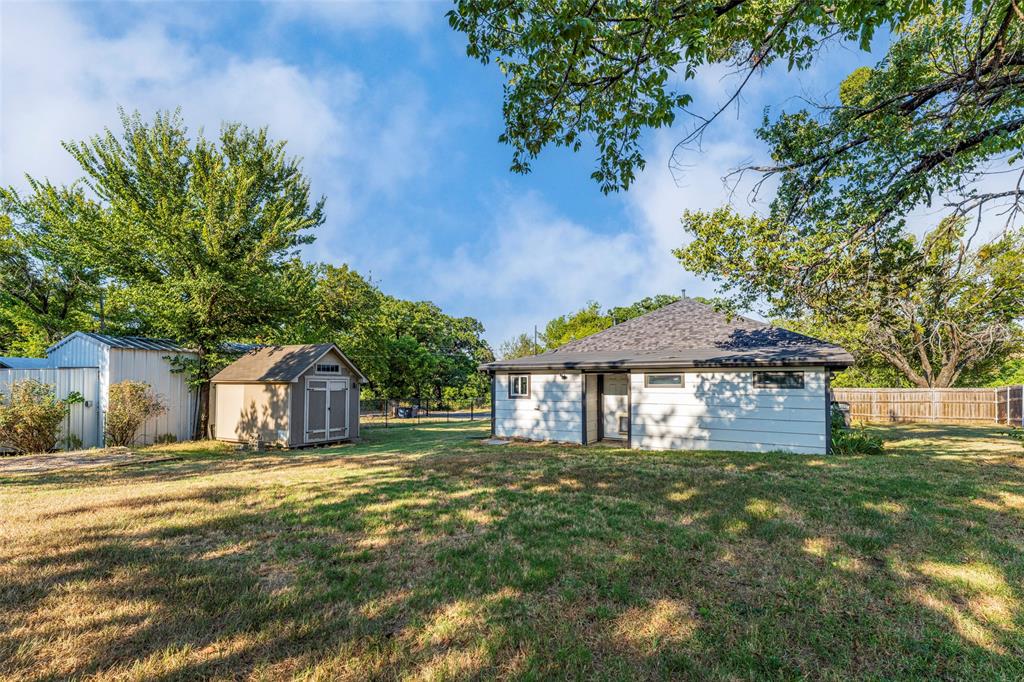 310 North Road Kennedale, TX 76060 - Photo 3 of 23 Expansive rear yard featuring a detached storage shed, a metal storage building, and a wood privacy fence