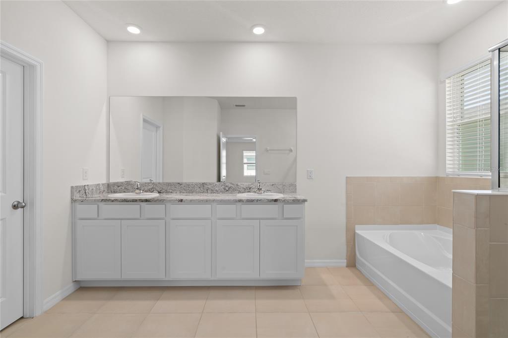 8260 Southwest 59th Avenue Ocala, FL 34476 - Photo 12 of 37 a bathroom with a granite countertop bathtub a sink and a window