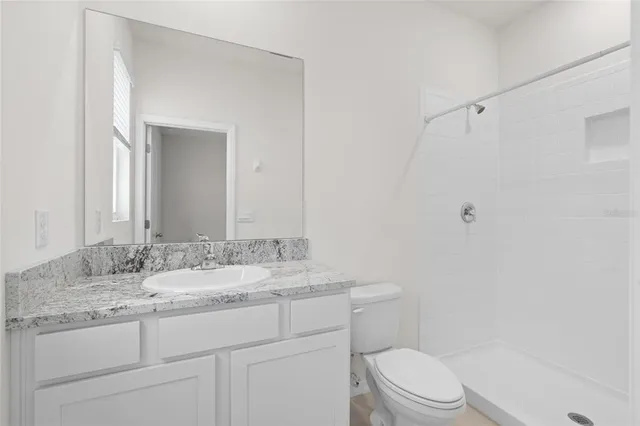 a bathroom with a granite countertop sink toilet a mirror and shower