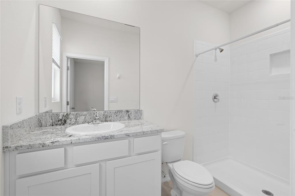 8260 Southwest 59th Avenue Ocala, FL 34476 - Photo 27 of 37 a bathroom with a granite countertop sink toilet a mirror and shower