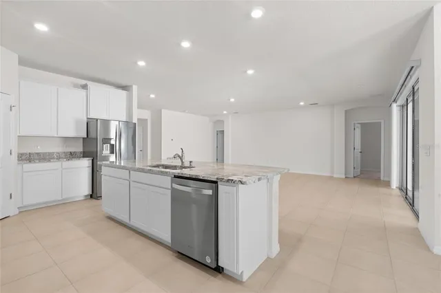 a kitchen with stainless steel appliances granite countertop a stove top oven a sink and white cabinets