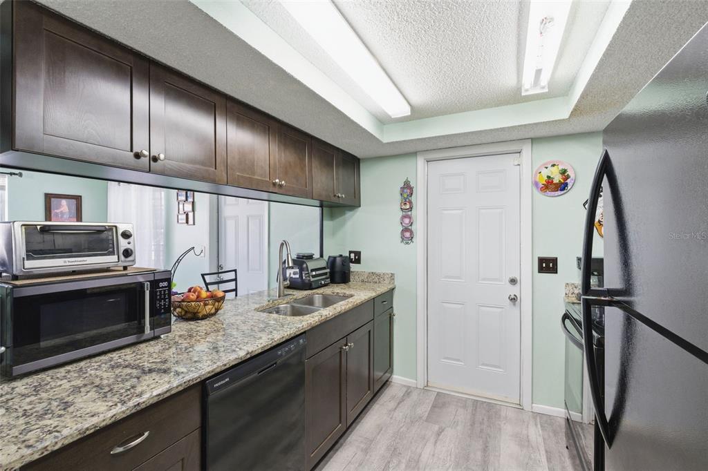 4904 Elmwood Street New Port Richey, FL 34653 - Photo 20 of 57 a kitchen with stainless steel appliances granite countertop a refrigerator a stove and a sink with wooden floor