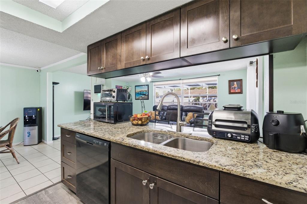 4904 Elmwood Street New Port Richey, FL 34653 - Photo 21 of 57 a kitchen with granite countertop stainless steel appliances a sink a stove refrigerator and cabinets