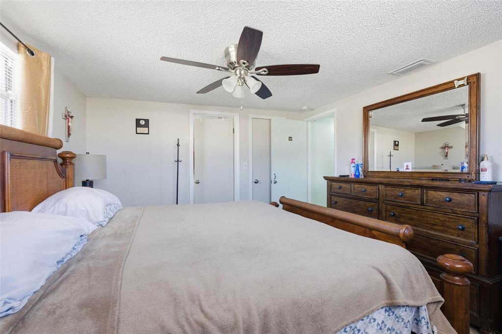 4904 Elmwood Street New Port Richey, FL 34653 - Photo 32 of 57 a bedroom with a bed and a large mirror with a chandelier