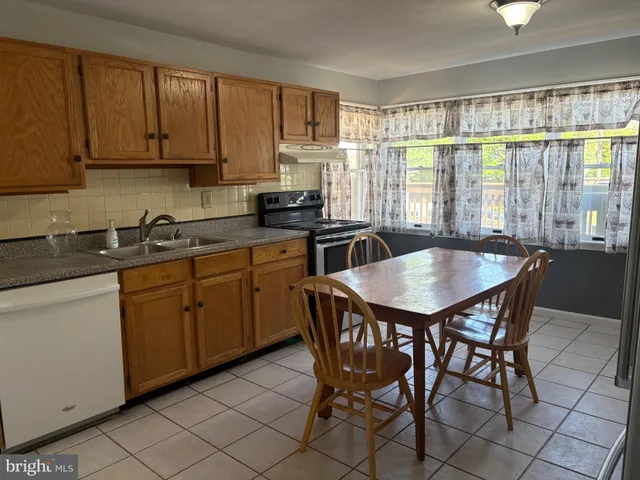 a kitchen with stainless steel appliances granite countertop a stove a sink a microwave dining table and chairs